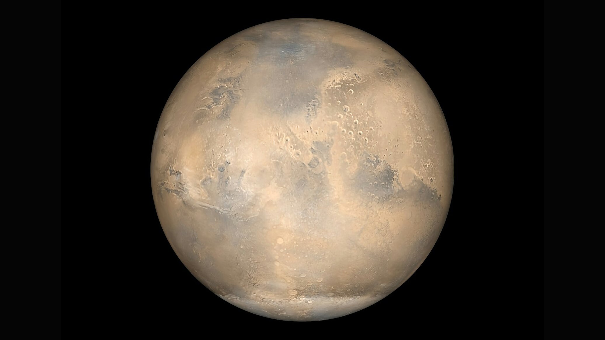 A pale, cratered planet against a black background, shown in a near-full view with beige and blue-gray patches.
