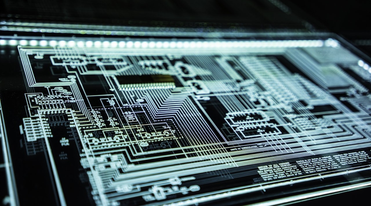 Close-up of a printed circuit board with dense white circuitry traces and small chips.