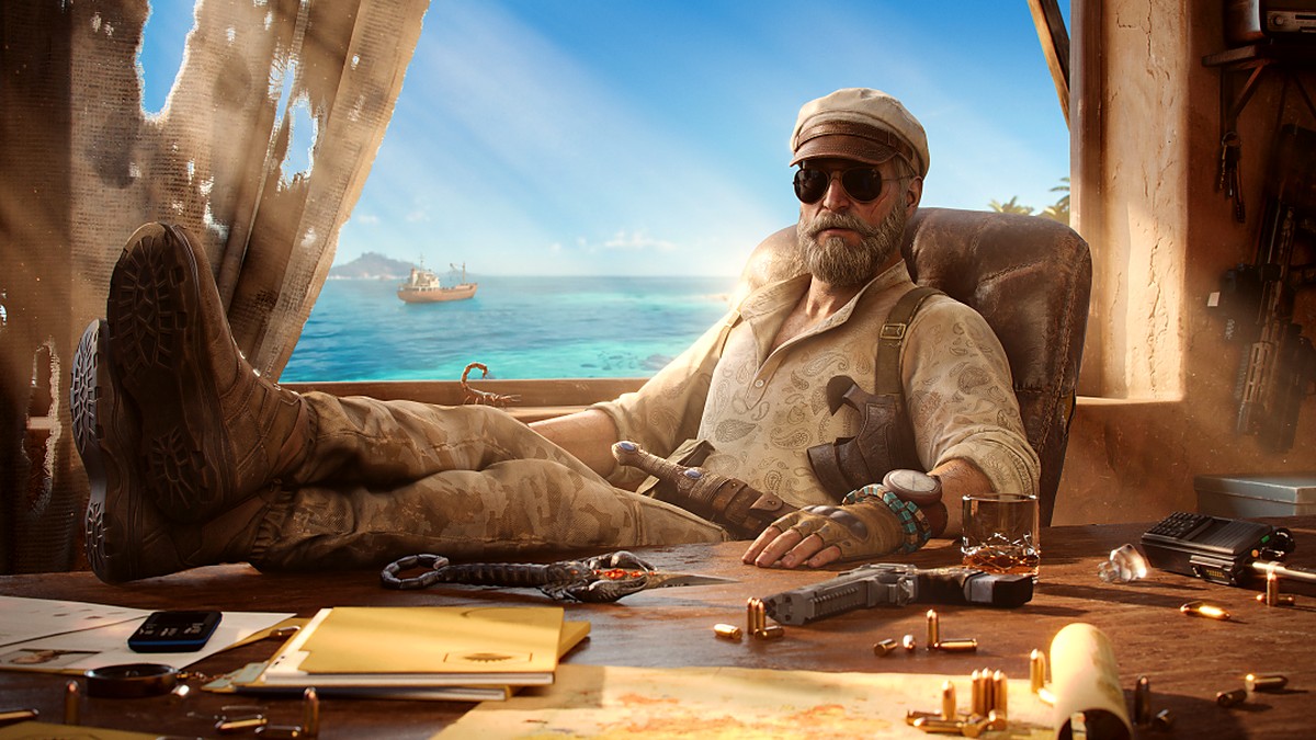 Bearded man in a cap and sunglasses lounges in a dusty coastal workshop, with guns, ammo, and papers on a cluttered desk.