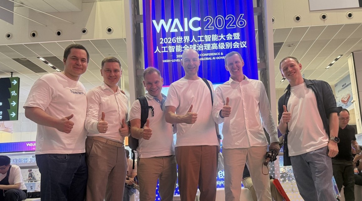 Six men in white shirts pose and thumbs up in front of a WAIC 2026 backdrop at a conference.