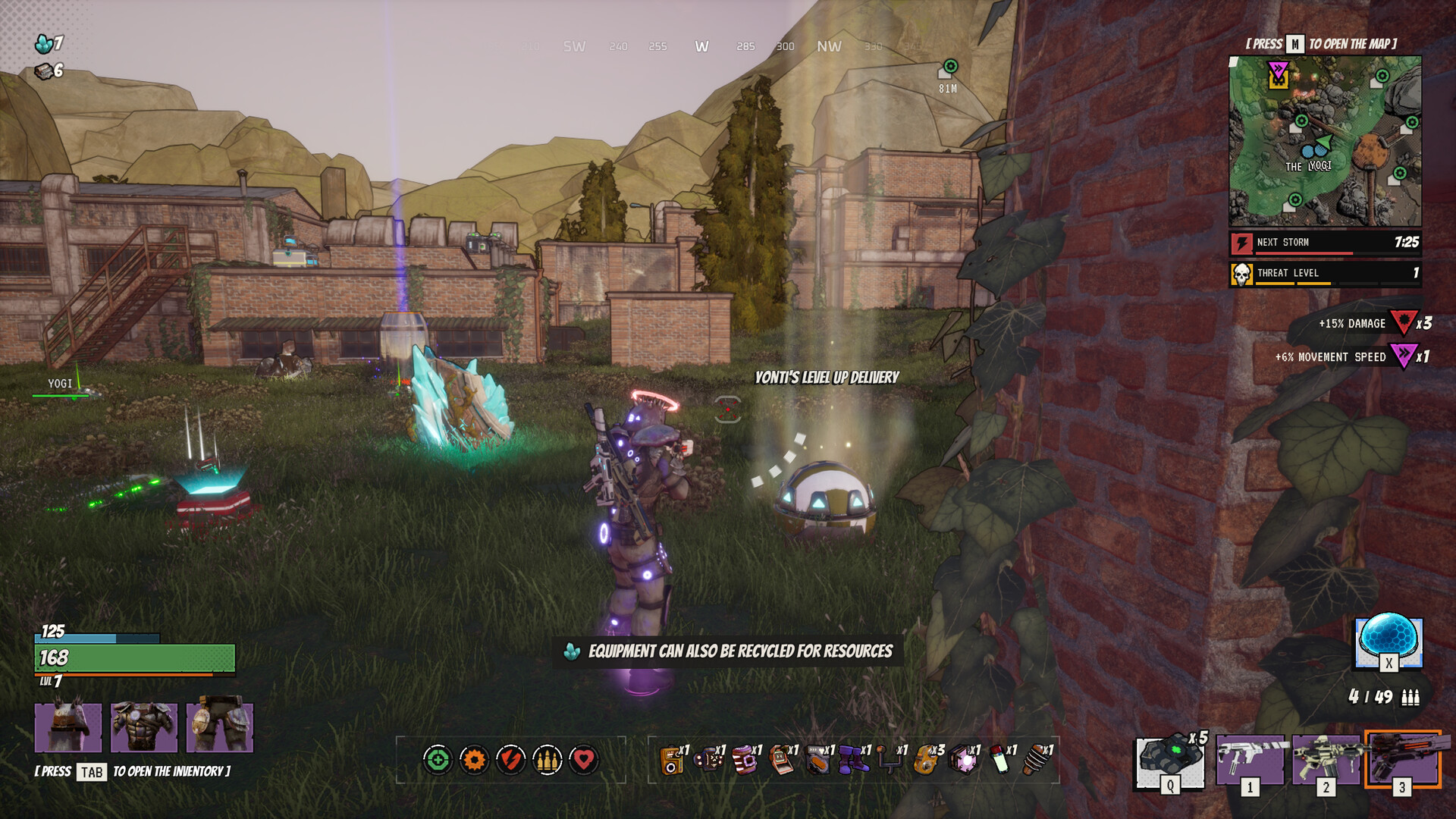 Player in futuristic armor stands in a grassy, overgrown compound with brick buildings and rocky hills in the background; glowing loot and tech devices lie nearby as a teammate raises a weapon.