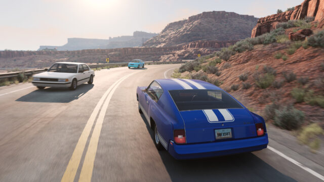 Blue muscle car with white stripes overtaking a sedan on a highway through red desert canyons
