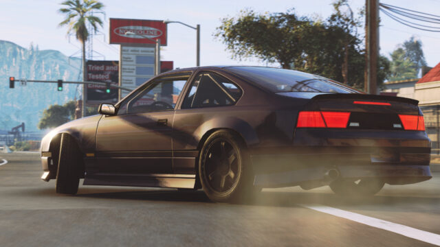 Black coupe drifting past a palm-lined gas station at a sunny town junction