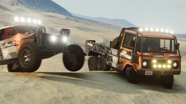 Trophy buggy jumping a sand dune next to an orange six-wheel support truck