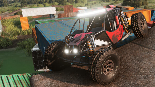Red-and-black tube-frame buggy climbing shipping containers on an off-road obstacle course